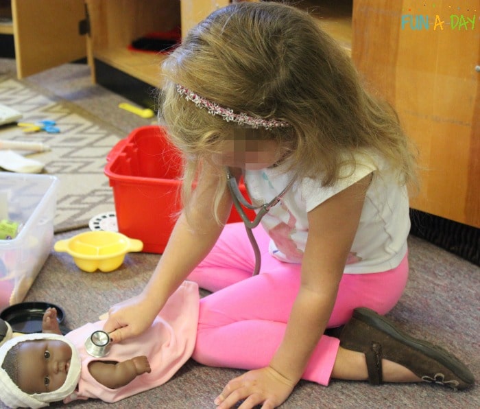 child playing doctor in preschool dramatic play center