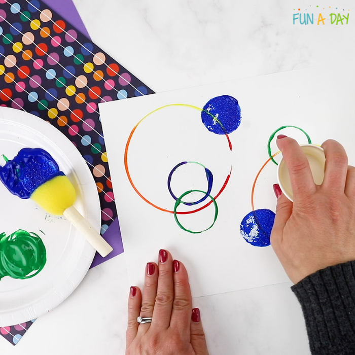a colorful circle painting being made with differently sized objects 