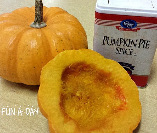 two pumpkins, one cut in half, sitting next to a tin of pumpkin pie spice