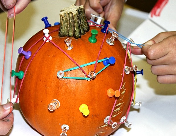 Children adding rubber bands to a pumpkin geoboard
