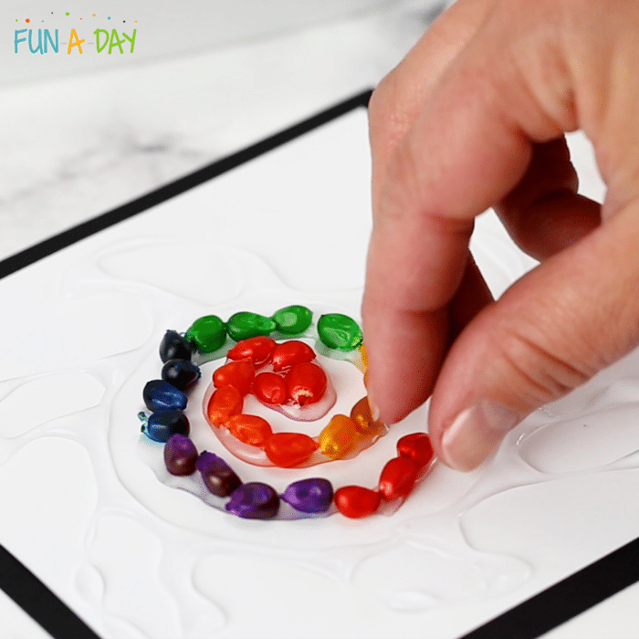 colorful popcorn kernels being formed into a spiral by an adult hand
