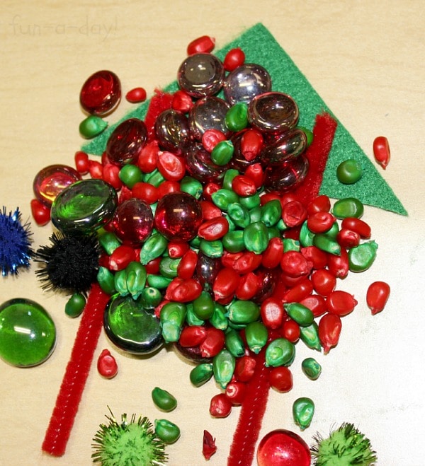 Pile of green and red corn kernels on top of green felt triangle and contact paper.
