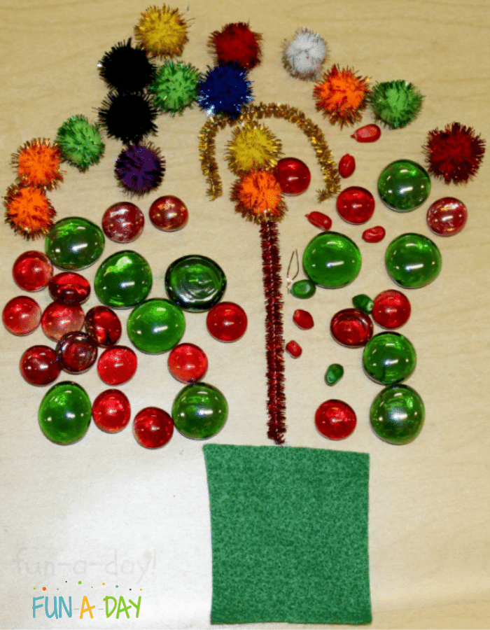 Child-made christmas tree made out of green felt, glass gems, pompoms, and colored corn kernels