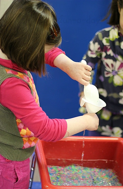 scooping and pouring water in the frog sensory bin