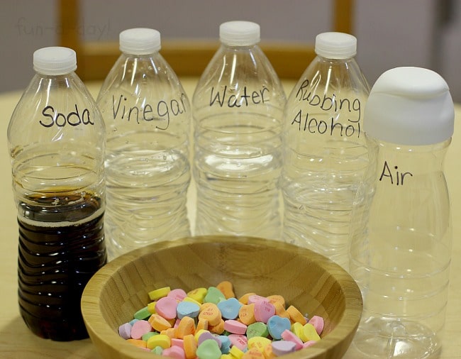 labeled plastic bottles with liquids and a bowl of conversation hearts
