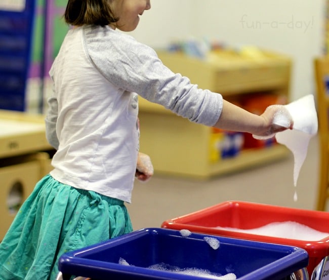 scooping spring-scented bubbles in a sensory bin