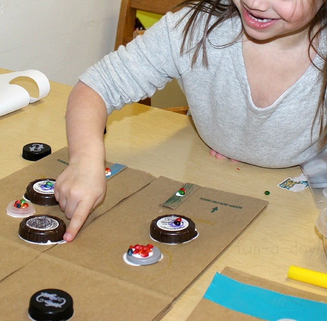 Gluing buttons on her robot vest - Easy Robot Craft Made from Recycled Materials