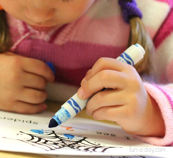 preschooler drawing spiders on her printable emergent reader