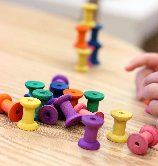 stacking is one of many fine motor skills activities kids can do with small dyed wooden spools