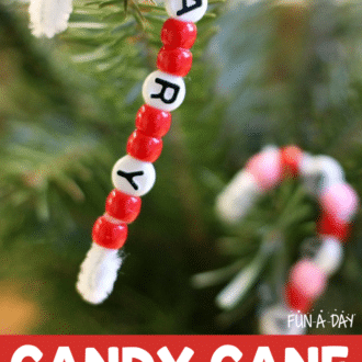 a completed beaded candy cane name ornament hanging on a Christmas tree with the text, 'candy cane ornament craft'