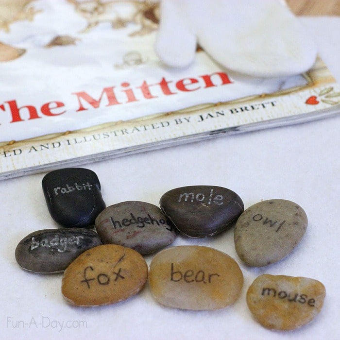 the back of the mitten story rocks with the animals of the mitten written out - rabbit, badger, hedgehog, mole, owl, fox, bear, mouse