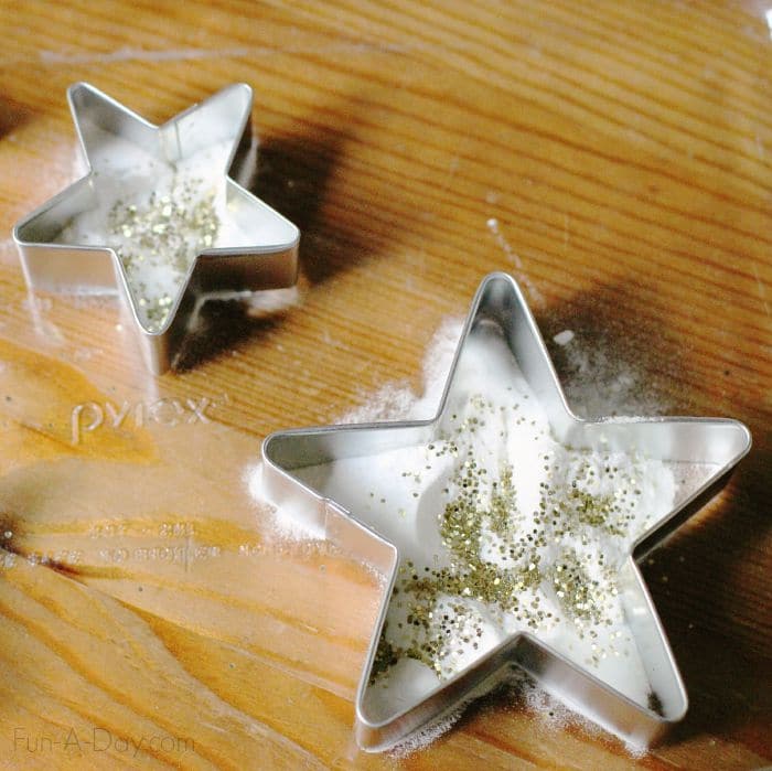 Star cookie cutters with baking soda and glitter in a glass dish.