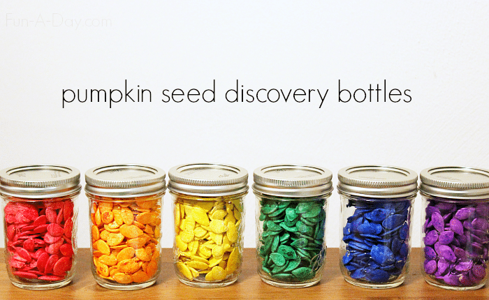 dyed pumpkin seeds in glass jars with text that reads pumpkin seed discovery bottles