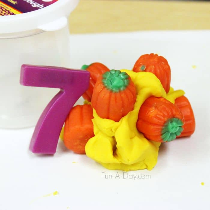 magnetic number 7 with seven pumpkin candies held together by yellow play dough