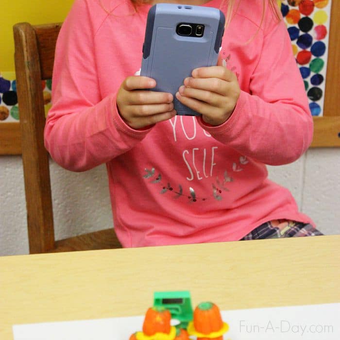 Using my phone to record her pumpkin math and engineering creation - such a fun fall S.T.E.M. activity for preschoolers