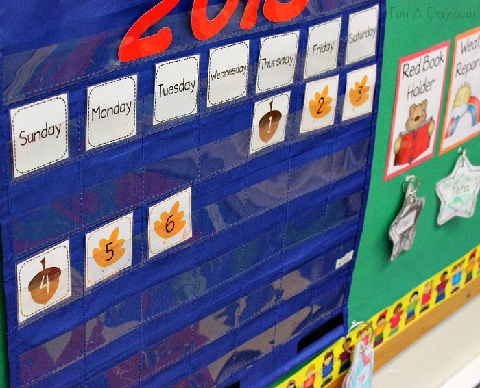 Acorn and leaf calendar numbers in a blue pocket chart calendar up on a bulletin board.