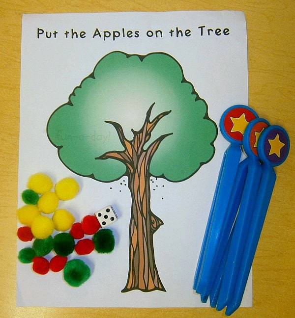 'Put the Apples on the Tree' math game with child tweezers, a die, and pompoms.