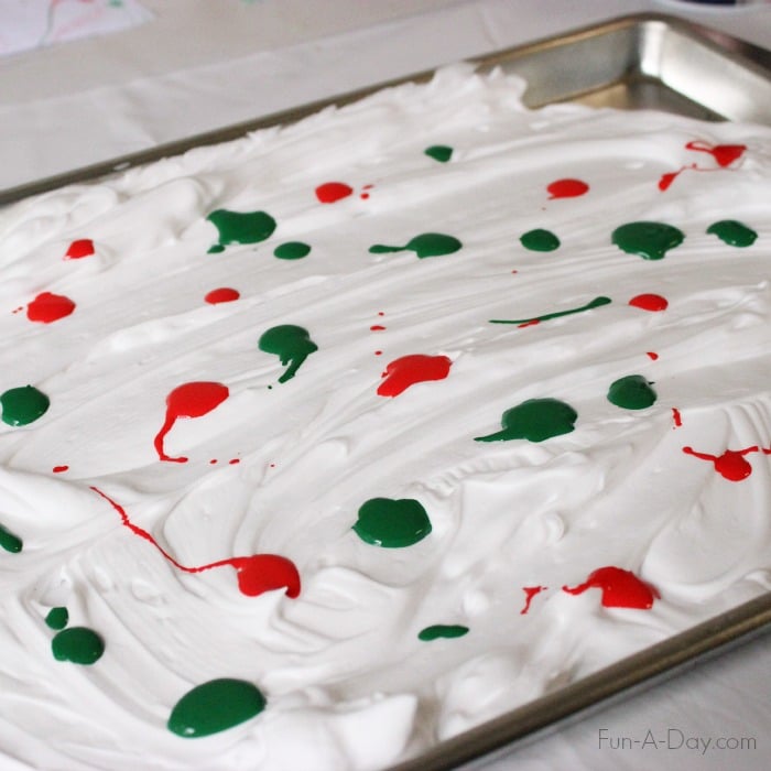 red and green drops of paint on top of shaving cream that has been smoothed into a tray