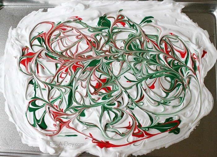 red and green paint swirled together in shaving cream to resemble marble