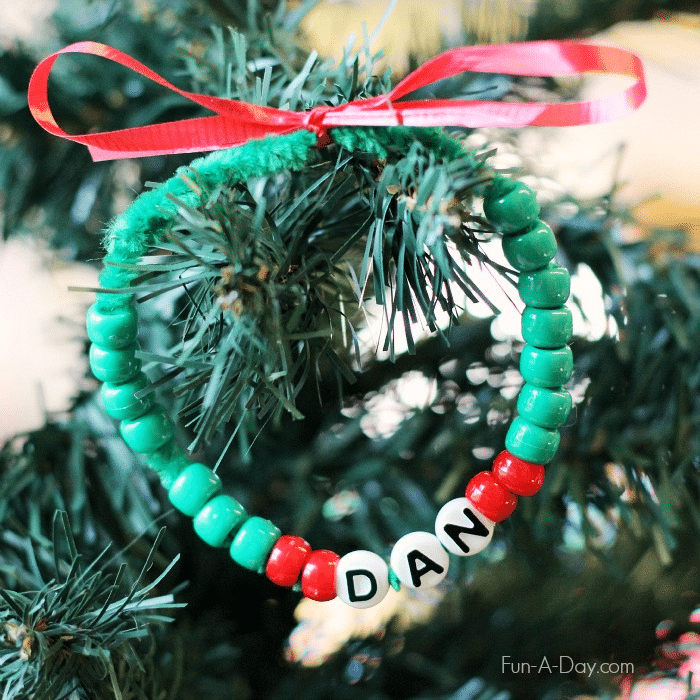 Child's beaded wreath craft made with red pony beads, green pony beads, and letter beads spelling Dan.