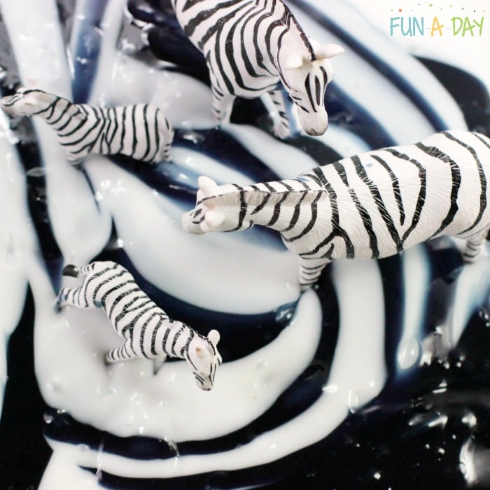 White and black slime swirled together with zebra toys in it.