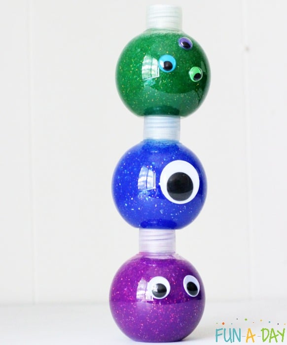 purple, blue, and green round monster slime sensory bottles stacked on top of each other