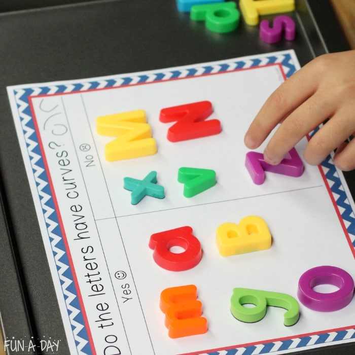 Child letter sorting on free printable magnetic letter mat.