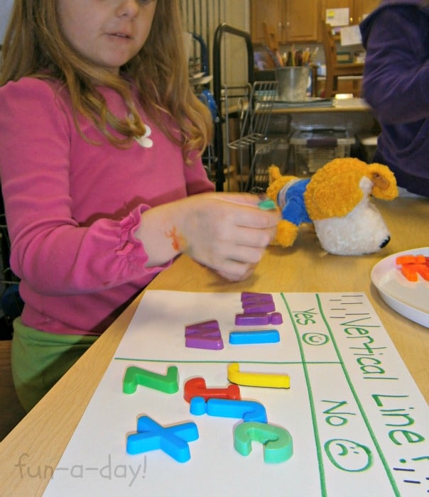 Preschool child learning about the alphabet while sorting magnetic letters.