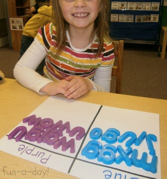 Preschooler smiling and proud after she's sorted purple and blue magnetic letters.