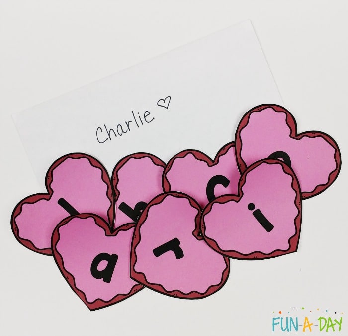 the name charlie on a card with the heart letters to spell his name in a pile on top