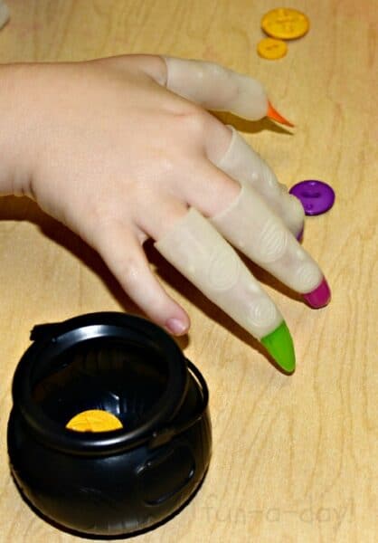preschool child wearing witch fingers to pick up buttons