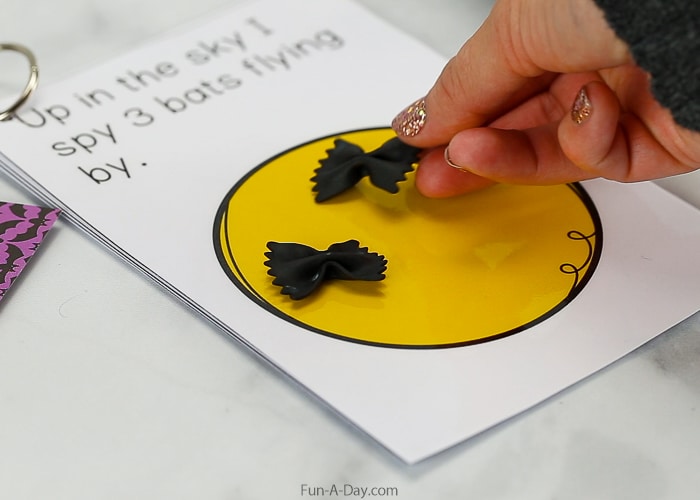 fingers placing bow tie pasta bats onto a math mat