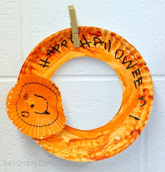 child made halloween wreath made from cupcake liner and paper plate