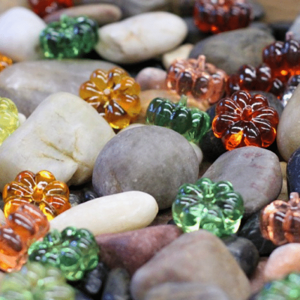 Small rocks and acrylic pumpkins on a tray.