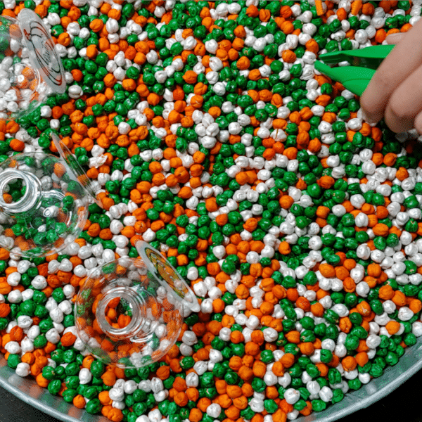child using tweezers to sort dyed chickpeas in a pumpkin sorting sensory activity