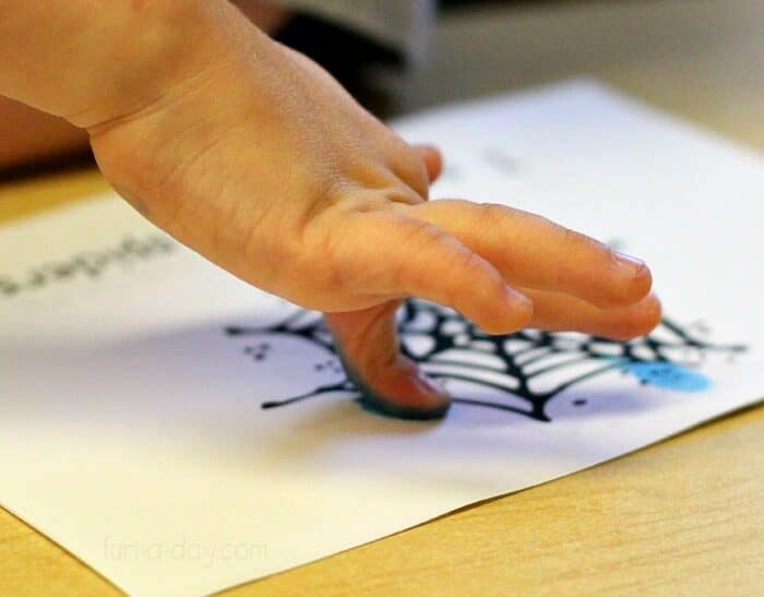 child using her fingerprint to add add spider illustration to spider counting book