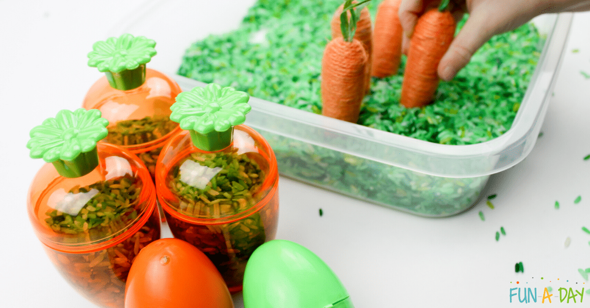 carrot easter eggs filled with dyed green rice as child pretends to plant toy carrots in a sensory bin