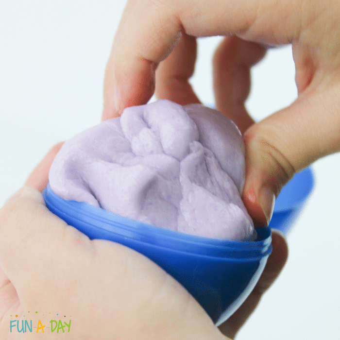 child putting peeps play dough into a blue plastic egg