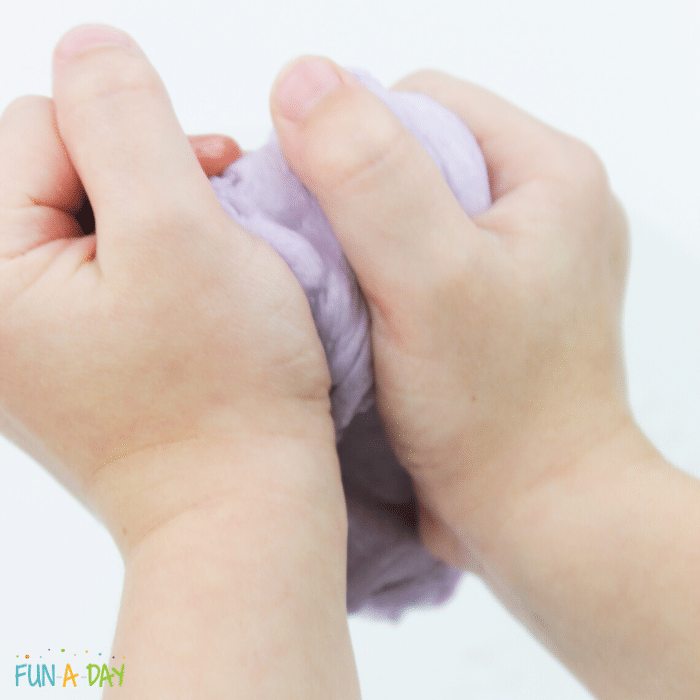 child's hands squeezing purple peeps slime