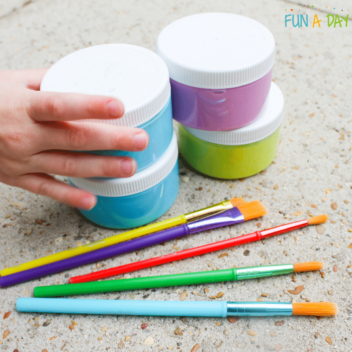 child hand grabbing a container of sidewalk chalk paint