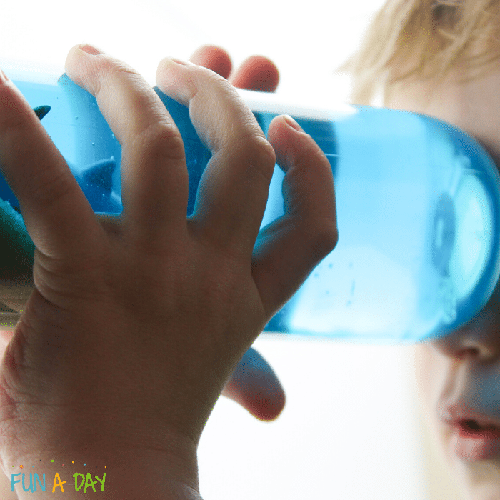 child holding shark sensory bottle up to his eye