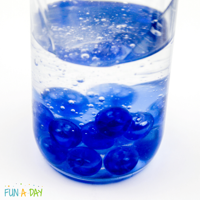 sensory jar with water and blue marbles