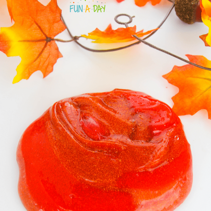 Reddish-orange fall slime with fall leaves in the background.