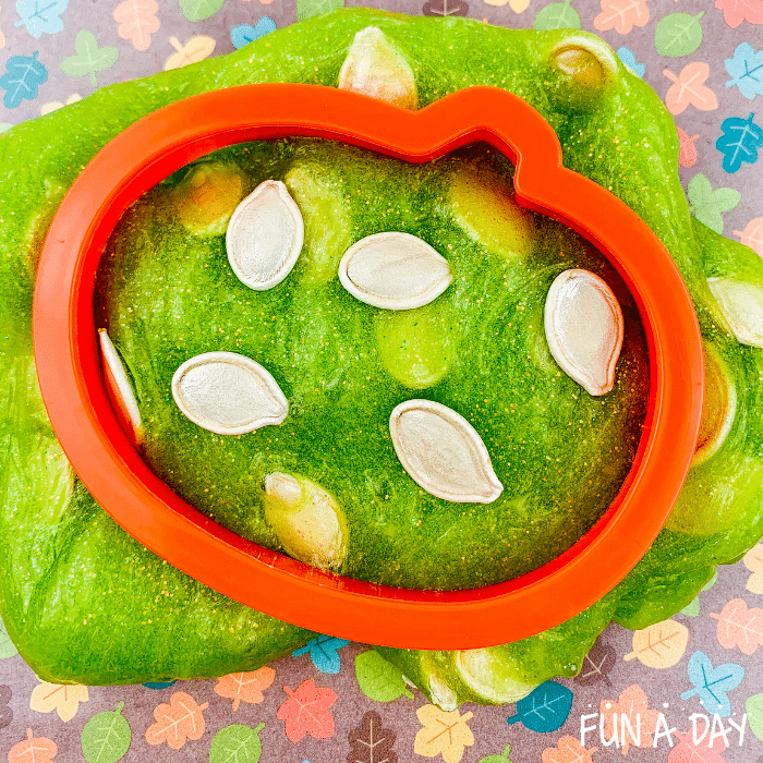 Green pumpkin seed slime with a pumpkin cookie cutter on top.