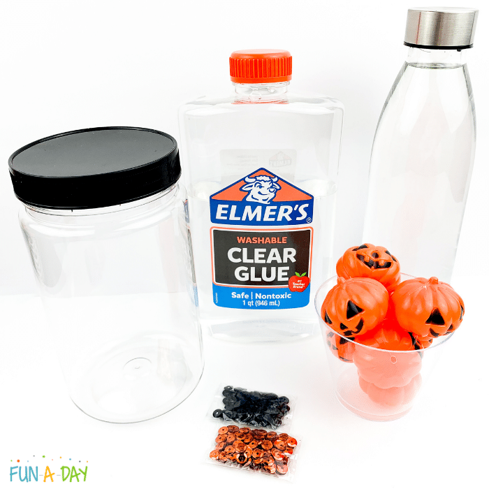 Materials to make a sensory bottle - empty jar, clear glue, water, black and orange sequins, and plastic jack-o-lanterns.