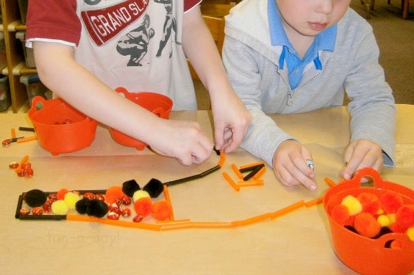 two preschool children making art on sticky paper with Halloween colored items