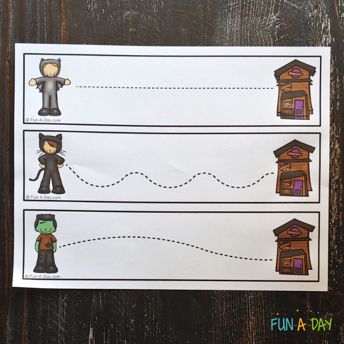 Printable halloween tracing sheets with dotted line connecting trick-or-treater clip art on the left to haunted house clip art on the right.