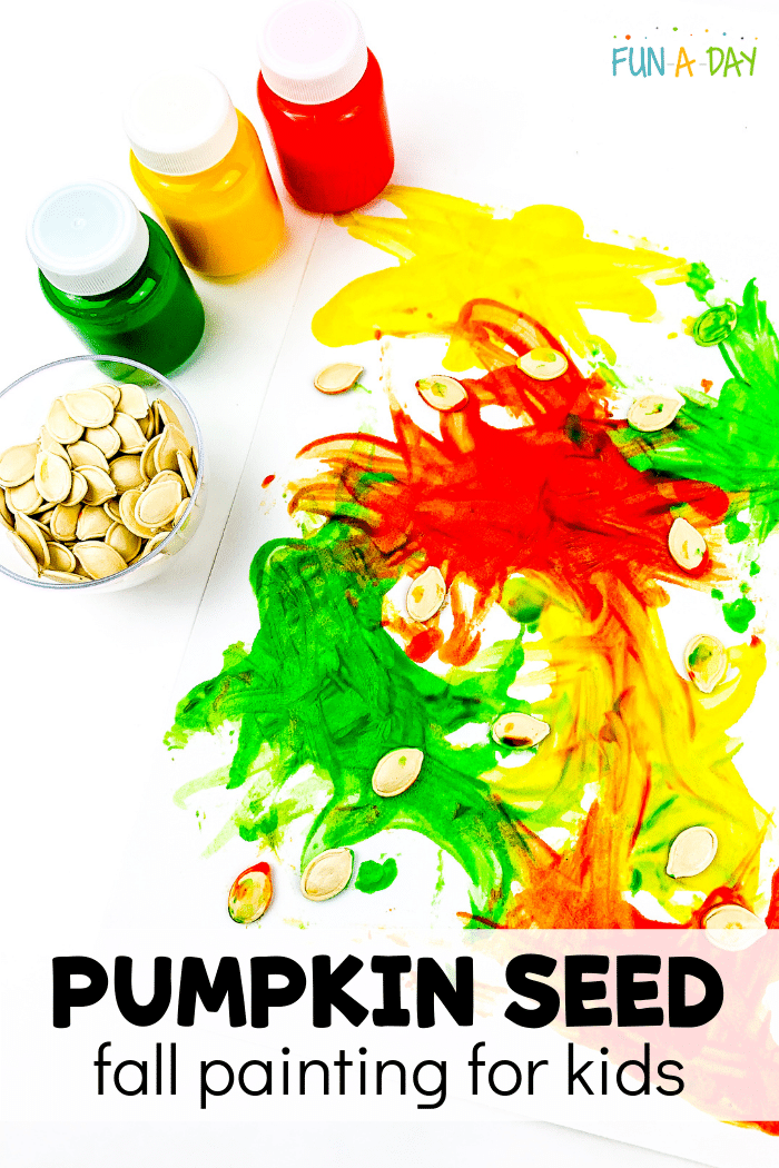 Green, yellow, and red paint bottles, a small bowl of pumpkin seeds, and pumpkin seed art in progress.