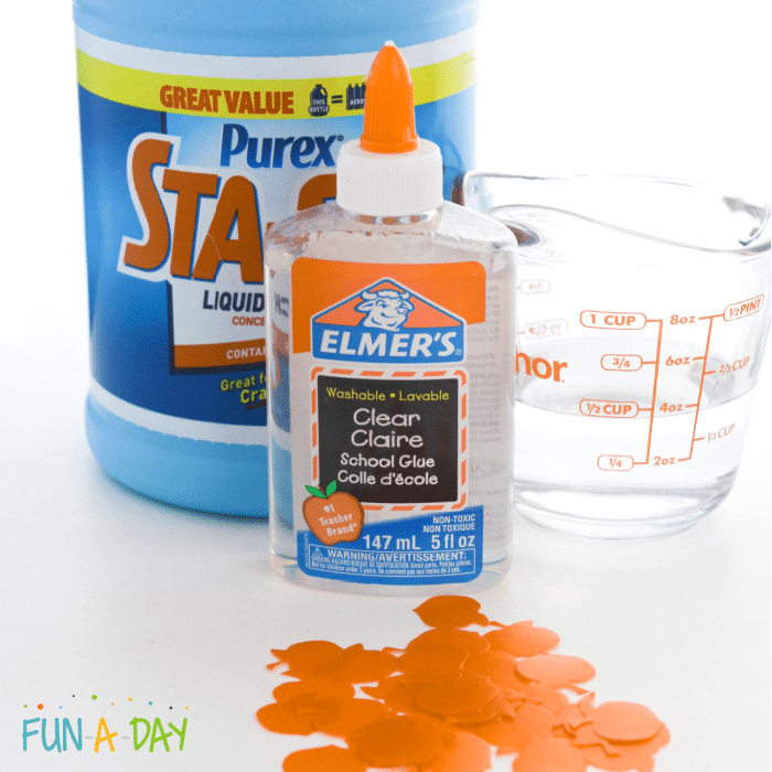 Ingredients which include liquid starch, clear Elmer's school glue, measuring cup with half cup of water, and orange pumpkin glitter.