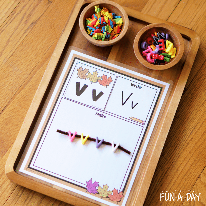 Fall alphabet mat on a wooden tray with letter Vv card and V beads on a pipe cleaner.